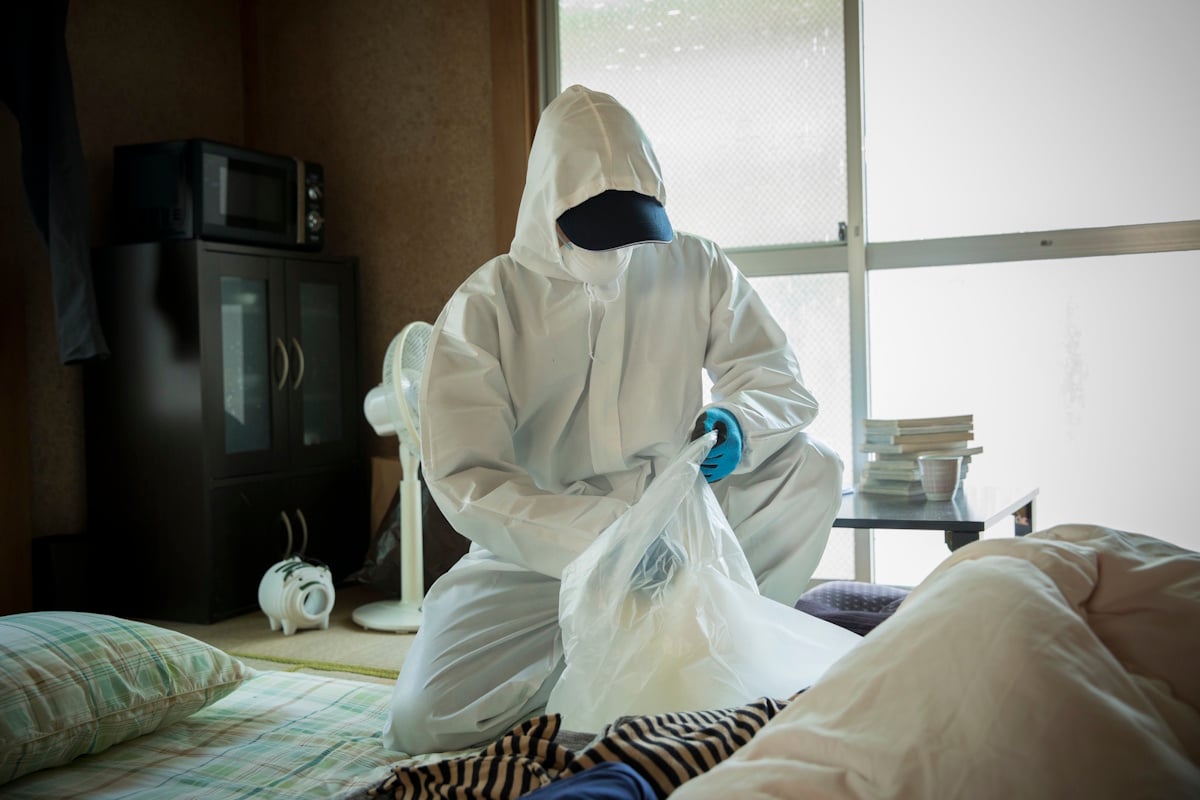 A worker in protective gear cleans up a house after a death