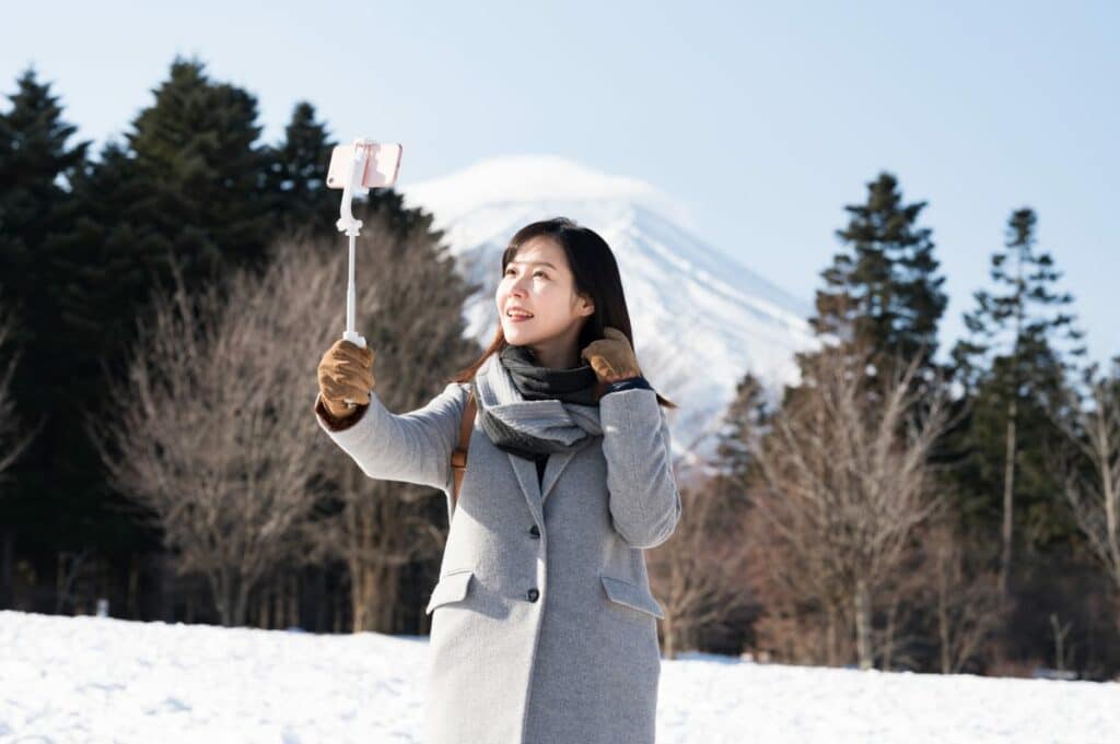 Woman using selfie stick in front of Mt. Fuji