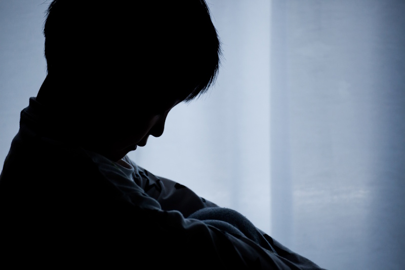 Child in silhouette looking despondent