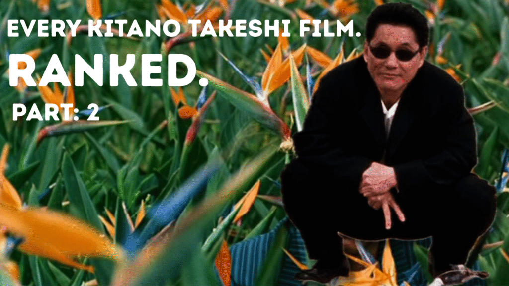 Kitano Takeshi crouches in a suit, with his fingers pointing downwards with two fingers revealed in a baseball single. He's superimposed over a bed of birds of paradise flowers.