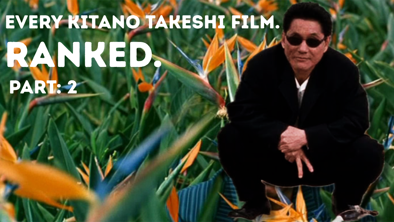 Kitano Takeshi crouches in a suit, with his fingers pointing downwards with two fingers revealed in a baseball single. He's superimposed over a bed of birds of paradise flowers.