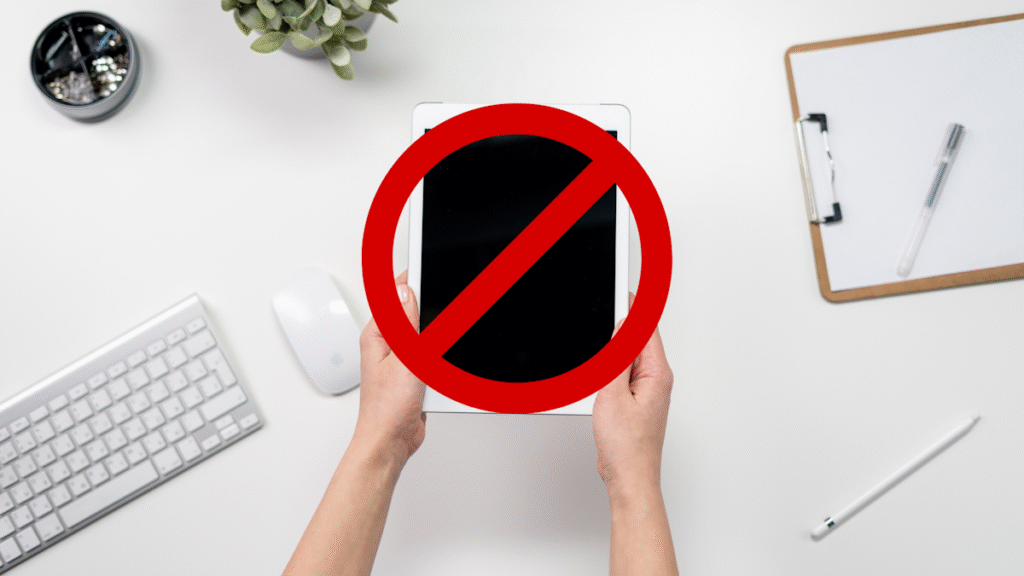 Picture of hands holding iPad with a banned symbol superimposed over the iPad