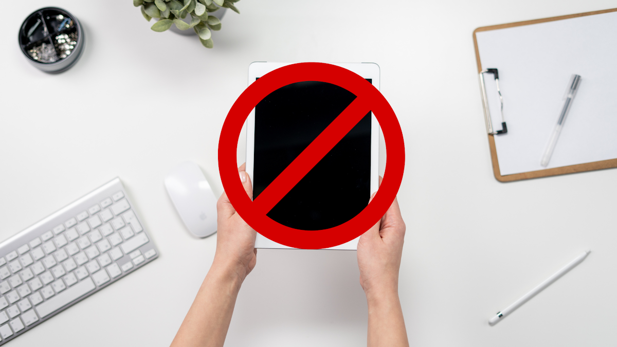 Picture of hands holding iPad with a banned symbol superimposed over the iPad