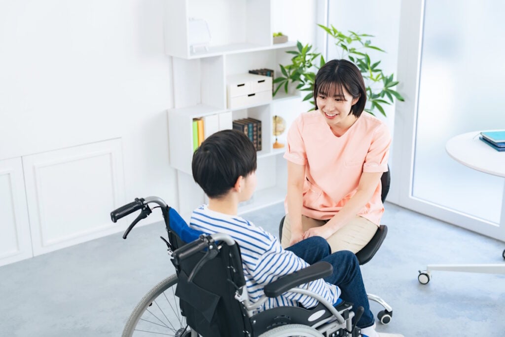 Young boy in wheelchair talking to nurse