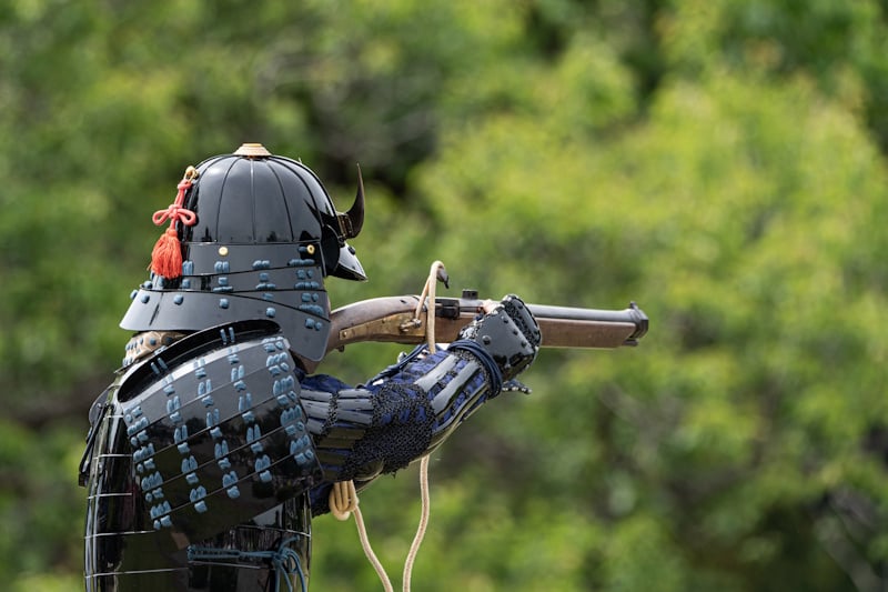 A man dressed as a samurai firing a matchlock
