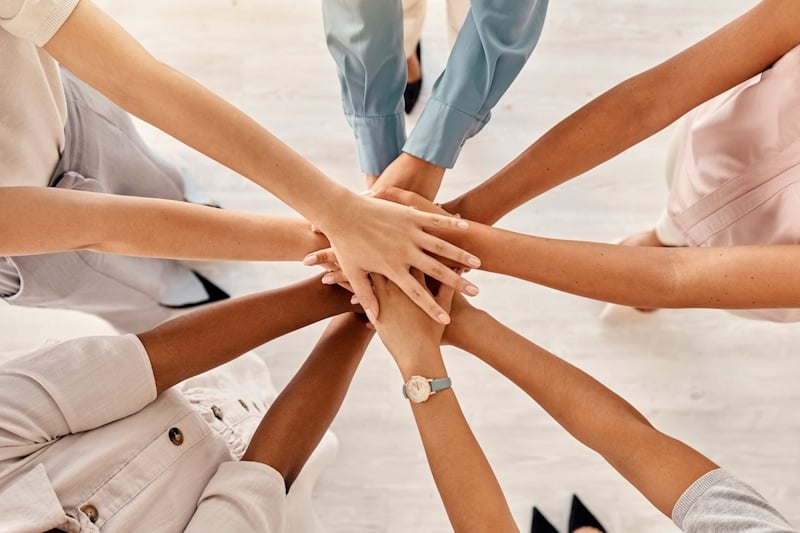 A group of people of various nationalities with their hands held together in a circle
