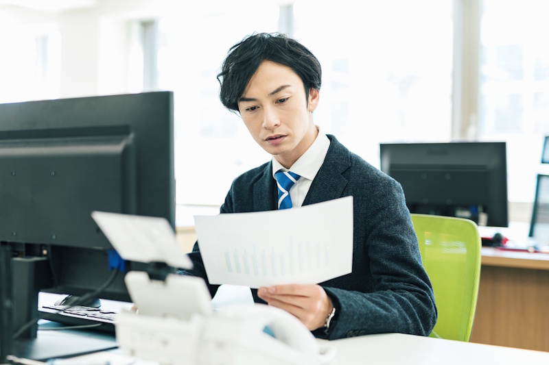 Man in business suit as desk looking through various papers