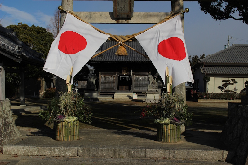 Two Japanese flags crossed over one another on a Shinto shrine