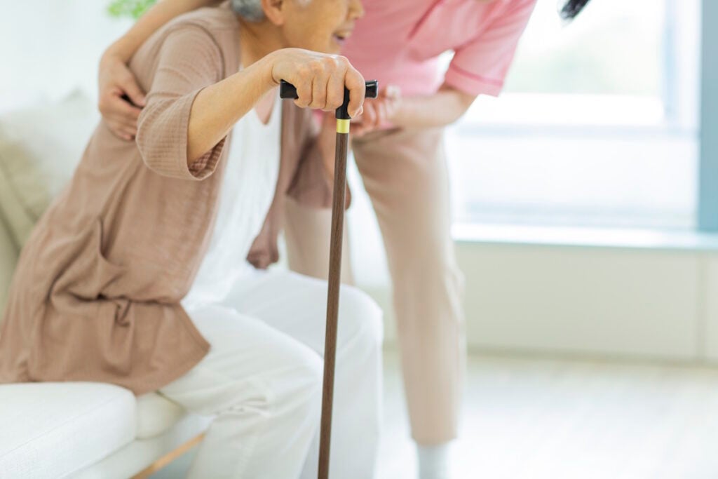 Health care worker helping an elderly woman to stand