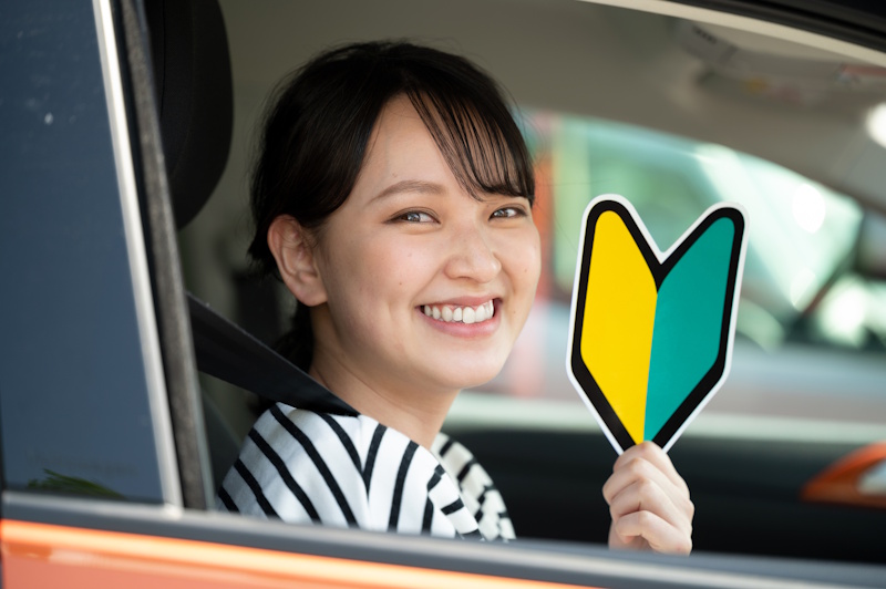 Woman holding up a beginner driver's mark
