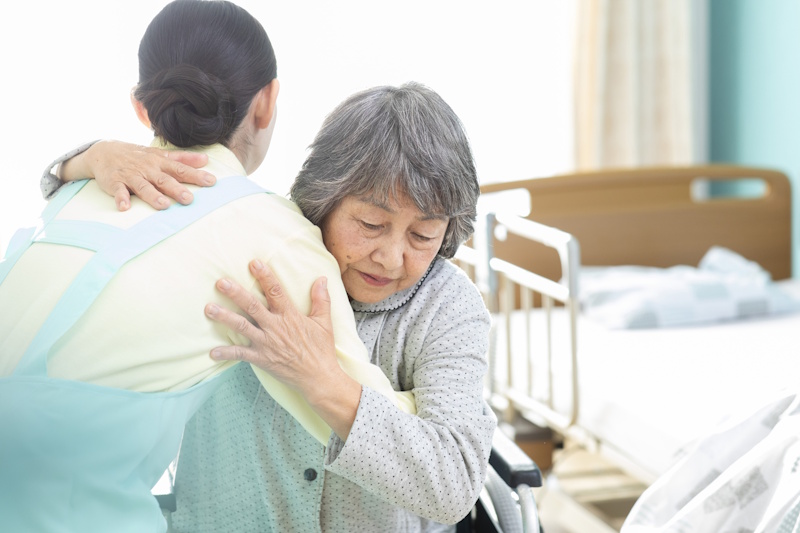 Nursing home worker helping woman out of wheelchair