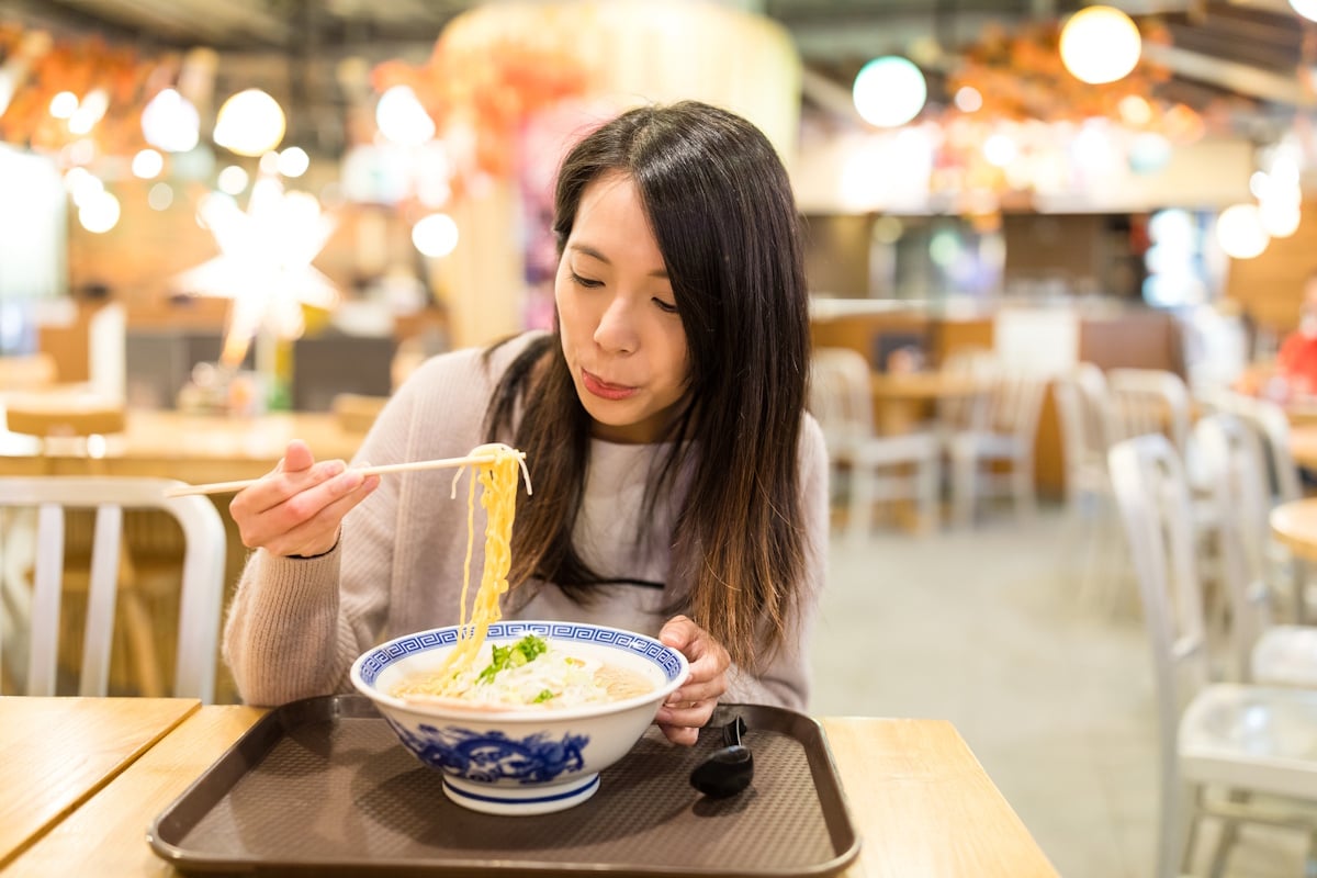 Woman blowing on ramen before eating it