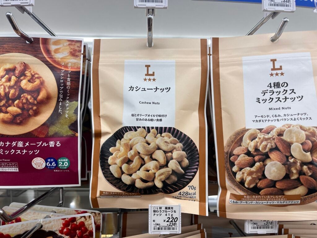 Bags of cashew nuts and mixed nuts on a convenience store shelf in Japan, with Japanese product labels.