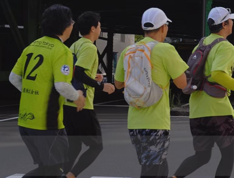 Yamathon participants in lime green bibs walk together along a Tokyo street.