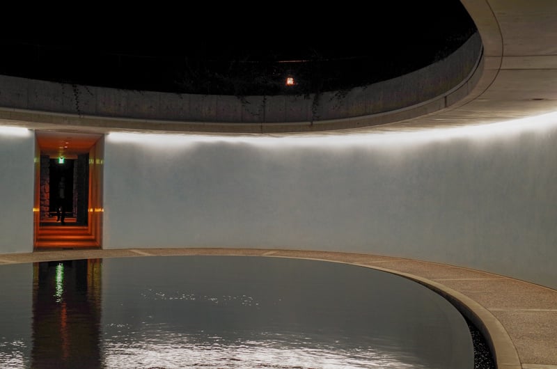 Curved concrete interior with a circular reflecting pool inside Benesse House Museum, Naoshima